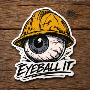 May include: A die-cut sticker featuring a graphic illustration of a human eyeball wearing a yellow construction hard hat. The eyeball has visible red veins and a dark iris. Below the eyeball, the text EYEBALL IT is printed in bold black letters.