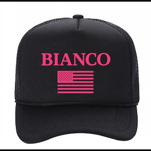 May include: Black trucker hat with the word "BIANCO" in pink block letters above a pink American flag graphic. The hat has a mesh back and a curved brim.