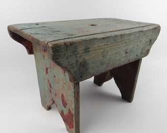 Minibanco primitivo de madera pintada, reposapiés rústico con pátina azul y roja.