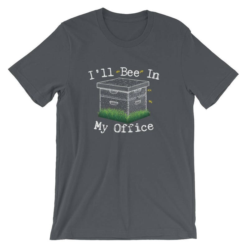 May include: Dark gray t-shirt with a white beehive and the text "I'll Bee In My Office" printed on the front.