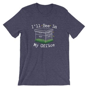 May include: A navy blue t-shirt with a white graphic of a beehive and the text "I'll Bee In My Office".