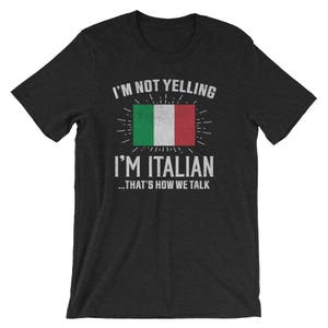 K&ouml;nnte beinhalten: Schwarzes T-Shirt mit wei&szlig;em Text, der "Ich schreie nicht, ich bin Italiener... so reden wir" lautet. Das Shirt zeigt ein abgenutztes italienisches Flaggen-Motiv.
