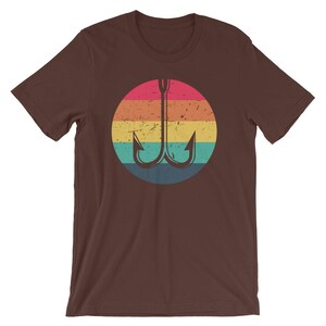 K&ouml;nnte beinhalten: Ein braunes T-Shirt mit einem Retro-Regenbogen-Design mit einem Doppelhaken-Angelk&ouml;der.