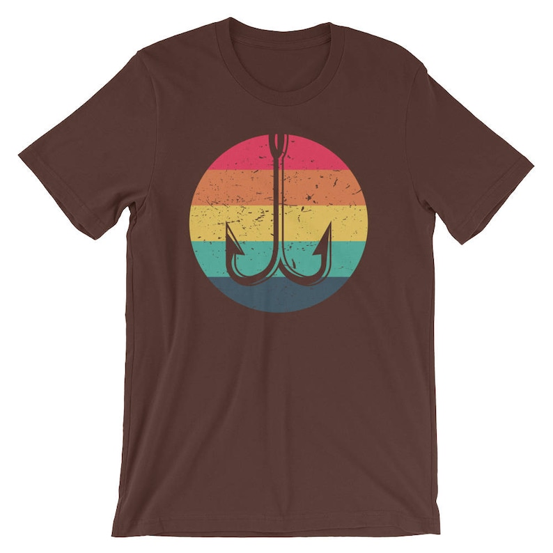 K&ouml;nnte beinhalten: Ein braunes T-Shirt mit einem Retro-Regenbogen-Design mit einem Doppelhaken-Angelk&ouml;der.