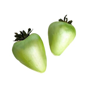 May include: Two green, shiny, heart-shaped strawberries with brown stems.