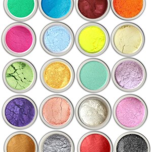 K&ouml;nnte beinhalten: Zwanzig runde Beh&auml;lter mit bunten Pigmenten, jeder mit einem anderen Farbton, darunter Gr&uuml;n, Blau, Rot, Orange, Pink, Gelb, Gold, Silber und Schwarz.