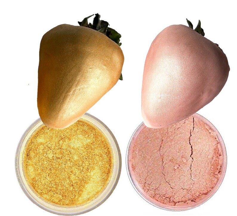 K&ouml;nnte beinhalten: Zwei Gl&auml;ser mit Kosmetik-Glitter, eines golden und eines rosa, mit einer goldenen und einer rosafarbenen Erdbeere auf jedem Glas.