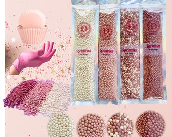 May include: Four bags of pearl sprinkles in white, rose gold, light pink, and gold. Each bag contains 150 grams of sprinkles. The sprinkles are in a variety of sizes and shapes. The bags are labeled "Sprinkles" and have a pink and white design.
