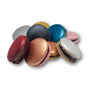 May include: A collection of nine colorful macarons, including silver, gold, teal, pink, red, and copper. The macarons are arranged in a pile on a white background.