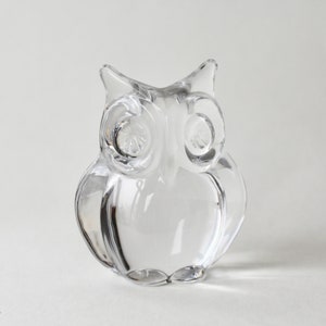 May include: A clear glass owl figurine. The owl has large, round eyes and a detailed beak.