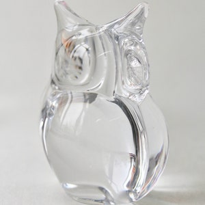 May include: A clear glass owl figurine. The owl is sitting on a white surface.