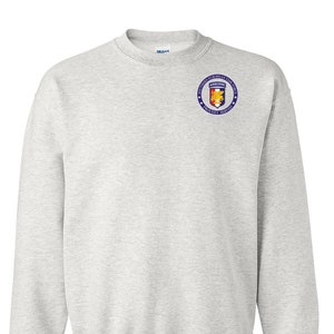 May include: A gray sweatshirt with a blue and yellow embroidered patch on the left chest. The patch features a circle with stars and the text "SOUTHERN EUROPEAN TASK FORCE AIRBORNE PROUDLY SERVED".