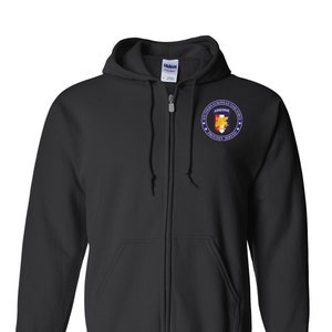 May include: Black zip-up hoodie with a patch on the left chest. The patch is a circle with a blue border and white stars. Inside the circle is a red shield with a yellow eagle and the words "Southern European Task Force" and "Proudly Served" in white.