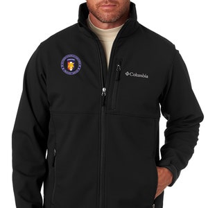 May include: Black softshell jacket with a zipper closure and a Columbia logo on the left chest. The jacket has a patch on the left chest with the text "European Command" and a seal.