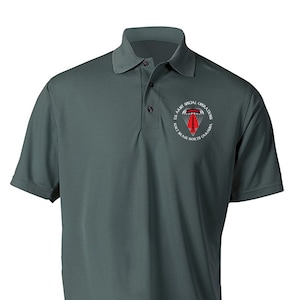 May include: A dark green polo shirt with a white embroidered patch featuring the text "U.S. ARMY SPECIAL OPERATIONS FORT BRAGG NORTH CAROLINA" and a red and gray parachute design.