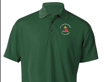 May include: A green polo shirt with a white embroidered patch featuring a yellow triangle with a red and blue design. The patch reads "1st Armored Division Old Ironsides".