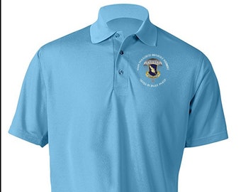 Puede incluir: Una camisa polo azul claro con un parche bordado en el pecho izquierdo. El parche presenta un paracaídas, un águila alada y el texto "501st PARACHUTE INFANTRY REGIMENT" y "DEVILS IN BAGGY PANTS".
