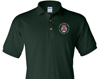 May include: A dark green polo shirt with a white embroidered patch featuring the text "101st Field Artillery Command" and a military insignia. The text below the insignia reads "Shock Reliable Accurate".