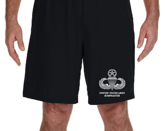 May include: Black athletic shorts with a silver United States Army Jumpmaster badge and text on the right leg.