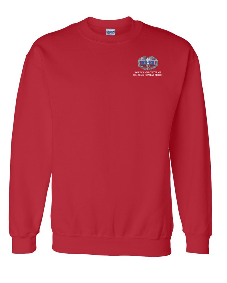 May include: Red sweatshirt with a white embroidered patch on the left chest. The patch features a silver Korean War Veteran badge with the text "KOREAN WAR VETERAN U.S. ARMY COMBAT MEDIC".