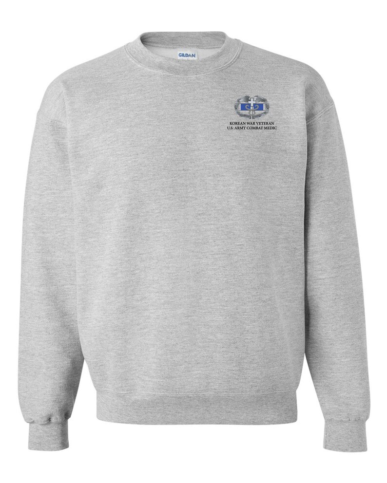 May include: A gray sweatshirt with a Korean War Veteran U.S. Army Combat Medic patch on the left chest.
