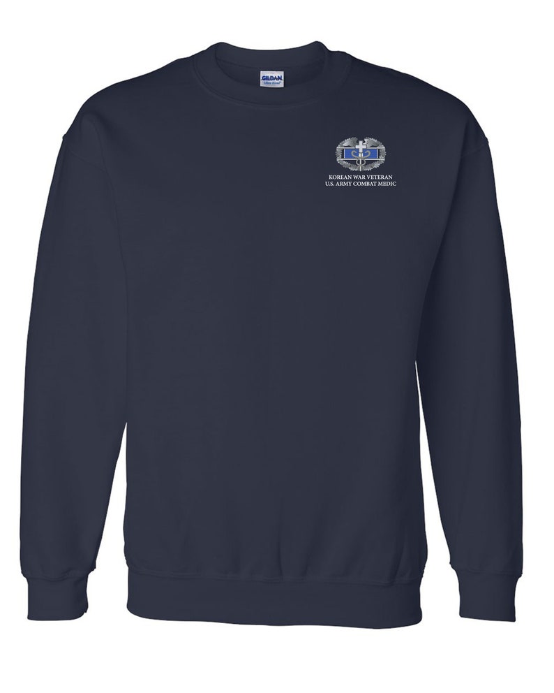 May include: Navy blue sweatshirt with a white embroidered patch that reads "Korean War Veteran U.S. Army Combat Medic".