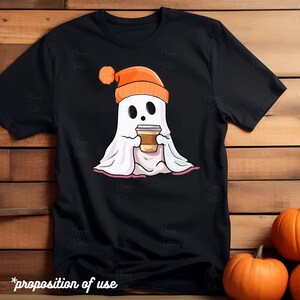 May include: Black t-shirt with a cartoon ghost wearing an orange beanie and holding a cup of coffee. The ghost is sitting on a pink blanket.