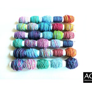 May include: A collection of colourful embroidery floss spools in shades of pink, green, blue, purple, and orange. Each spool is wrapped around a white cylinder. The image is set against a white background.