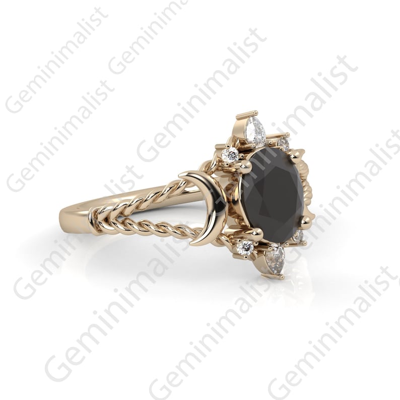 Puede incluir: Un anillo de oro con una piedra preciosa negra rodeada de piedras blancas m&aacute;s peque&ntilde;as. La banda del anillo es un dise&ntilde;o de cuerda trenzada con un detalle de media luna.