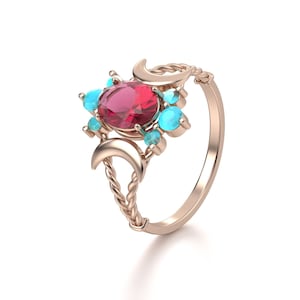 Könnte beinhalten: Roségoldener Ring mit einem großen ovalen Rubin, kleinen Türkissteinen und Mondsichel-Akzenten. Der Ring hat ein gedrehtes Band und ein zartes, himmlisches Design. Ein einzigartiges Schmuckstück.