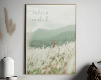 May include: A hand reaches up from a field of tall, white grass towards a hazy, green mountain range in the background. The text "to live for the hope of it all" is superimposed on the image.