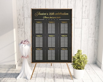 May include: A black chalkboard with a gold frame lists the seating arrangement for Jessica's 70th celebration. The chalkboard is on a gold easel and has the text "Jessica's 70th celebration" and "Please find your table" written in gold lettering.