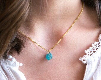 May include: A gold chain necklace with a small, light blue gemstone pendant.