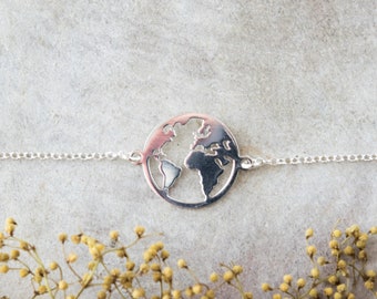 May include: A silver chain bracelet with a cut-out world map charm. The charm is a circle with the continents of the world cut out.
