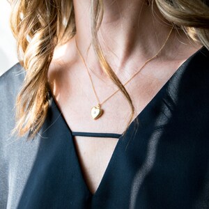 Pode incluir: Um colar de ouro com um pingente em forma de cora&ccedil;&atilde;o com um pequeno detalhe de diamante.