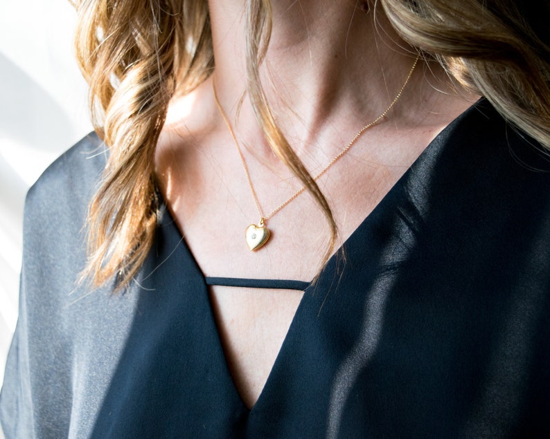 Pode incluir: Um colar de ouro com um pingente em forma de cora&ccedil;&atilde;o com um pequeno detalhe de diamante.