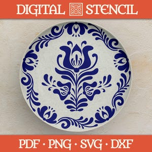 May include: A white ceramic plate with a blue floral design. The plate has a central floral motif and a border of stylized leaves and flowers. The words "DIGITAL STENCIL" are at the top, and "PDF • PNG • SVG • DXF" are at the bottom.