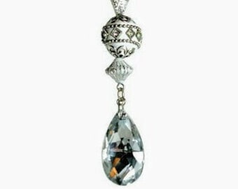 May include: A decorative crystal pendant with a silver chain. The pendant features a large teardrop-shaped crystal at the bottom, connected to a series of ornate silver beads and a round, white bead with diamond accents. The top has a clear, faceted bead.