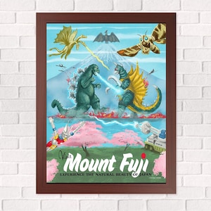 May include: A framed poster featuring a stylized illustration of Mount Fuji with various kaiju monsters, including Godzilla and Gigan, in a battle scene. The text reads Visit Mount Fuji EXPERIENCE THE NATURAL BEAUTY OF JAPAN with pink cherry blossoms.