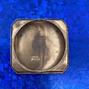 Peut inclure: Int&eacute;rieur d'un bo&icirc;tier de montre ouvert, de couleur dor&eacute;e, avec du texte visible. Le bo&icirc;tier est octogonal avec un int&eacute;rieur circulaire. Le texte comprend des chiffres et les mots "10K Gold Filled" et "Wadsworth Watch Co."