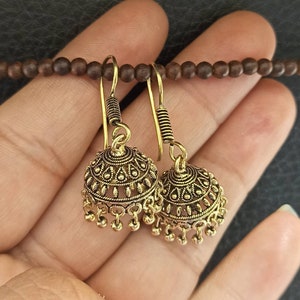 May include: A pair of gold-tone dangle earrings with intricate designs and small beads hanging from the bottom.