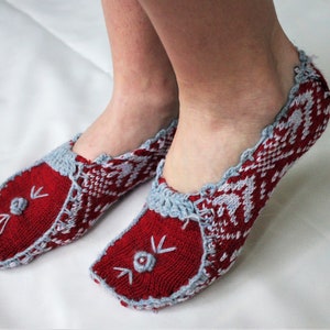 Puede incluir: Calcetines de pantuflas de punto rojo y azul con un patrón de copo de nieve blanco y una linda carita bordada en la punta.