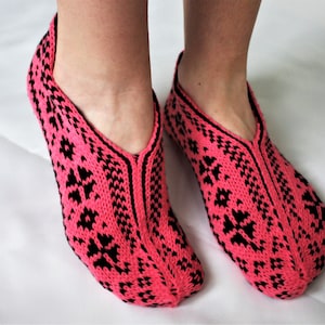 Puede incluir: Pantuflas de punto rosa y negro con un patrón geométrico.
