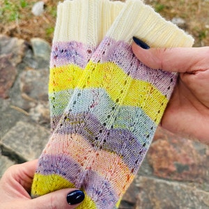 May include: A pair of colourful striped socks with a lacy pattern. The socks are made of a soft, knitted fabric and feature a variety of colours, including yellow, pink, purple, and blue.