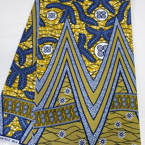 May include: A yellow and blue patterned fabric with a geometric design. The fabric has a white border with the text "SUPREME WAX HOLLAND" printed on it.