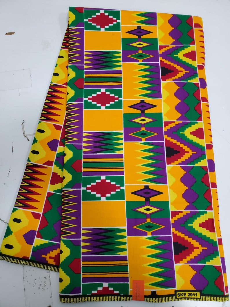 May include: A colorful fabric with a geometric pattern in shades of yellow, green, purple, red, and black. The fabric has a repeating pattern of diamonds and zigzags. The fabric is labeled "SKE 2011".
