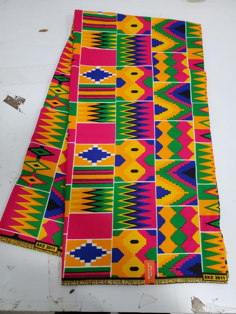 May include: A colorful fabric with a geometric pattern in shades of yellow, green, blue, pink, and black. The fabric has a repeating pattern of squares and triangles. The fabric is labeled "SKE 2011".