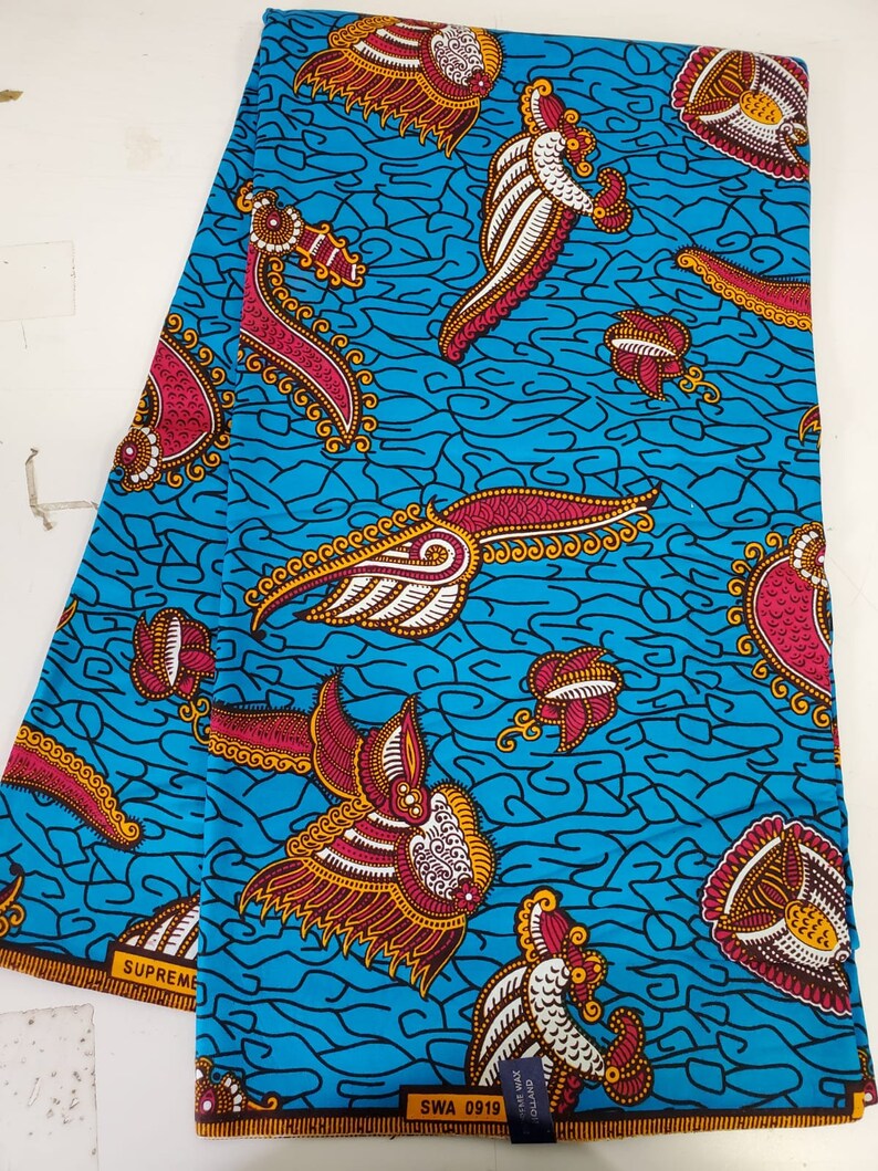 May include: A blue and white fabric with a repeating pattern of stylized birds with red, gold, and white accents. The fabric has the text "SUPREME" and "SWA 0919" printed on it.