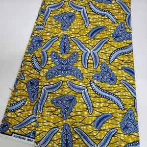 May include: Two pieces of yellow fabric with a blue and white leaf pattern. The fabric is labeled "Supreme Wax" and "Guaranteed Wax".