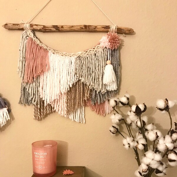 Bohemian pink and neutral wall decor featuring textured yarn, pom poms ans tassels, the boho wall hanging is perfect for bedroom and nursery